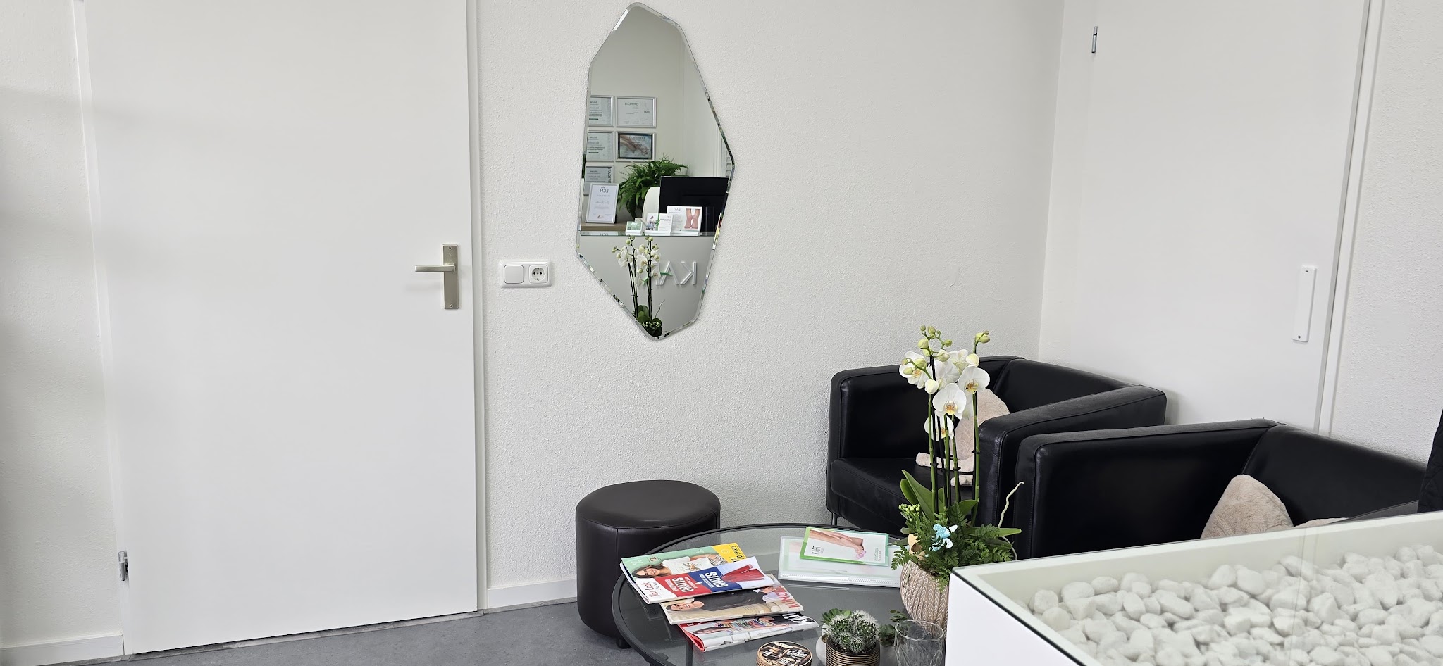 De wachtruimte met zwarte fauteuils, een orchidee en tijdschriften